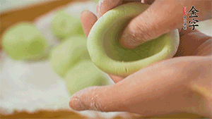 將均分的艾草面團(tuán)搓成圓，挖一個(gè)窩，放入餡心，再搓成圓。