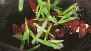 先后下香腸片、四季豆絲均勻翻炒，加適量清水燜煮一下。