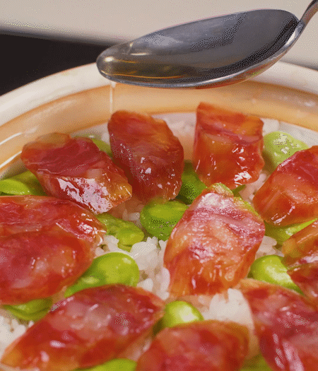 大米出現(xiàn)小孔時開蓋放香腸，往鍋邊淋入少許油，再燜煮8~10分鐘左右。