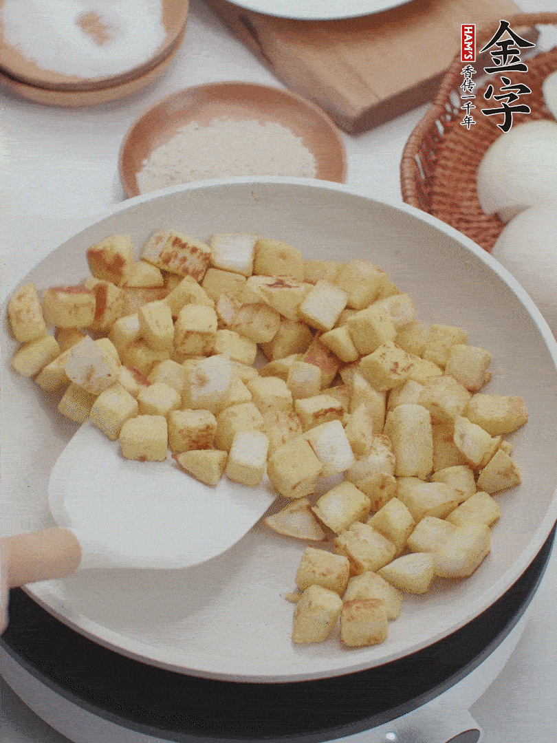 起鍋熱油，倒入饅頭丁，小火煎至蛋液凝固定型再翻面，饅頭丁部煎至金黃時(shí)盛起待用。