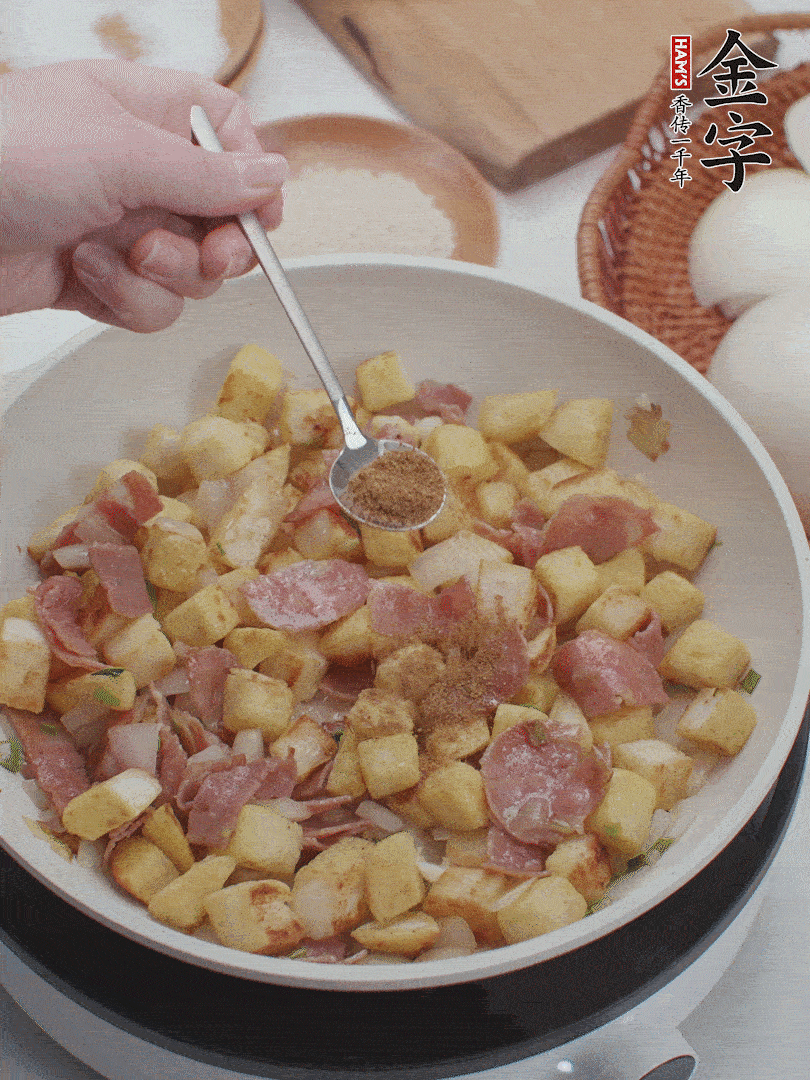 起鍋少油，煸香洋蔥丁、蔥白，加入金字培根火腿翻炒幾下，再加入饅頭丁、1小勺孜然粉、少許鹽翻炒均勻并鋪平。