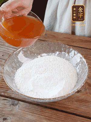 轉(zhuǎn)化糖漿、枧水、花生油攪拌均勻，加入面粉混合，醒發(fā)2小時(shí)。捏成23g一個(gè)的小球