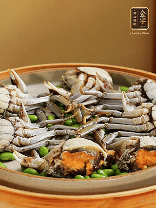 盤(pán)底鋪毛豆，依次放大閘蟹、咸肉， 淋一圈料酒、豉油。